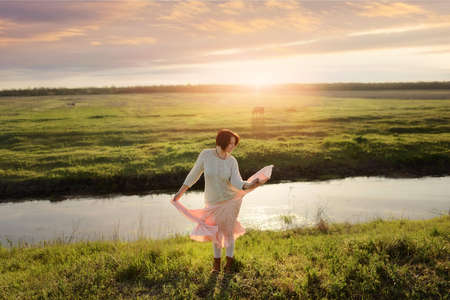 in the sunlight dancing girl pink skirt on a green glade near the riverの写真素材