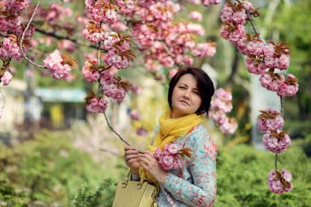cherry blossoms in the garden and a woman in a colorful dress and yellow scarfの写真素材