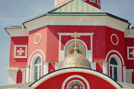 beautiful red and white church dome with a cross and an iconの写真素材
