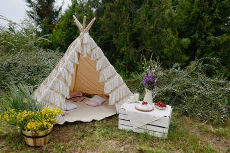 nature white tent on a bouquet of flowers and a box strawberries and milkの写真素材