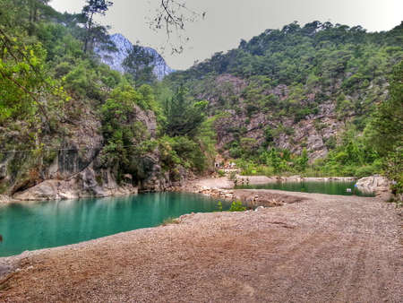 limpid lake beside the road on the background of green mountainsの写真素材