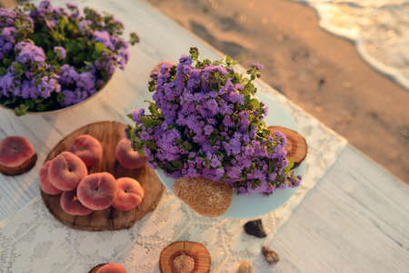 on a wooden table scattered ripe peaches and a bouquet of flowersの写真素材