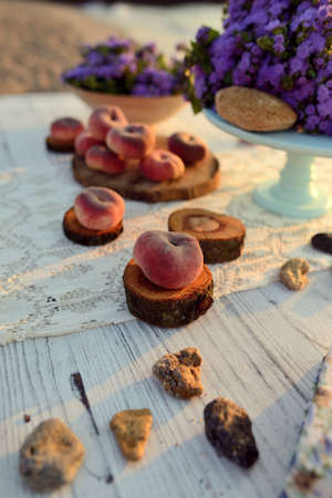 on a wooden table scattered ripe peaches and a bouquet of flowersの写真素材