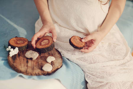 against the background of the abdomen of pregnant woman holding a wooden crafts and stonesの写真素材