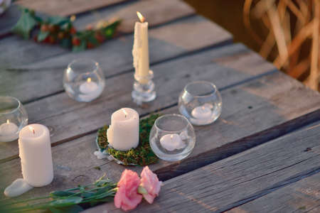 on a wooden bridge in the sun romantic arrangement of candles, glass and flowersの写真素材