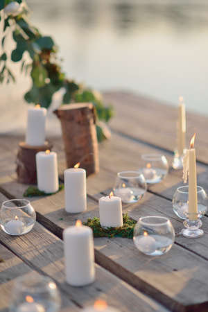 on a wooden bridge on the river in the sun romantic arrangement of candles, glassの写真素材