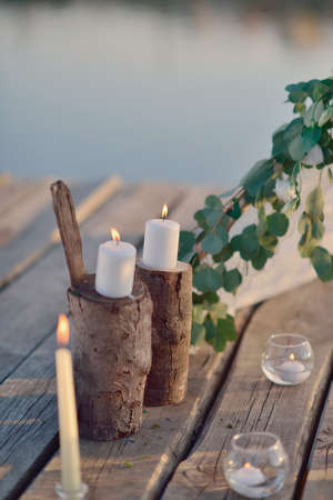 on a wooden bridge on the river in the sun romantic arrangement of candles, glassの写真素材
