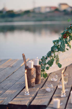on a wooden bridge on the river in the sun romantic arrangement of candles, glassの写真素材