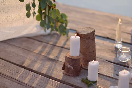 on a wooden bridge in the sun romantic arrangement of candles, glass and stumpsの写真素材