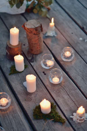 on a wooden bridge on the river at dusk romantic arrangement of burning candlesの写真素材