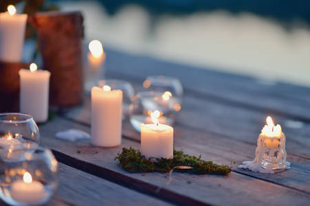 on a wooden bridge on the river at dusk romantic arrangement of burning candlesの写真素材