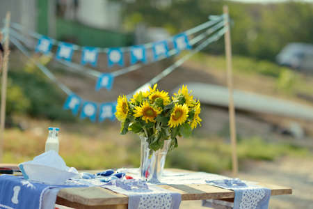 Outdoor wooden table with a bottle of milk and a vase with sunflowersの写真素材