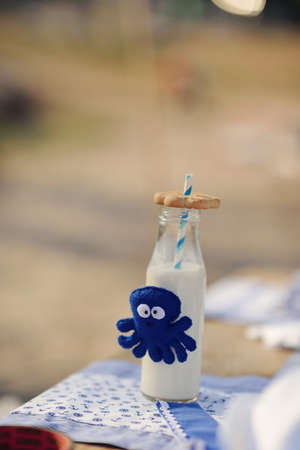 on a wooden table is a bottle of milk and a soft toy octopusの写真素材