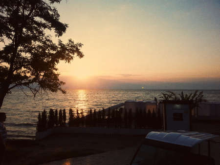 twilight sunset over the sea and the silhouette of the buildings and treesの写真素材