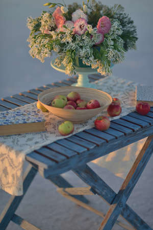 on a wooden table still life of apples and flowers in a vase