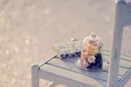 on a white wooden chair decorative bulb with a bouquet of roses and a bookの写真素材