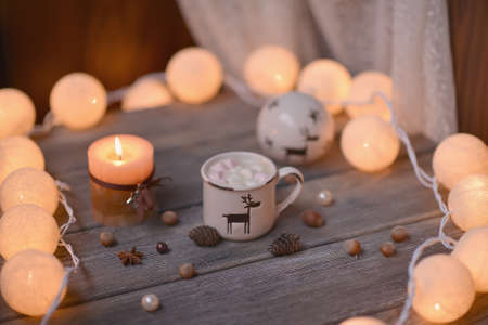 on wooden table lit garland and candle in a cup of coffee and nutsの写真素材