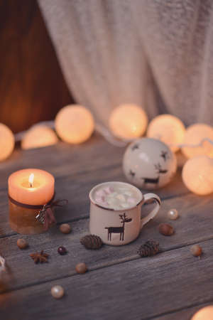 on wooden table lit garland and candle in a cup of coffee and nutsの写真素材