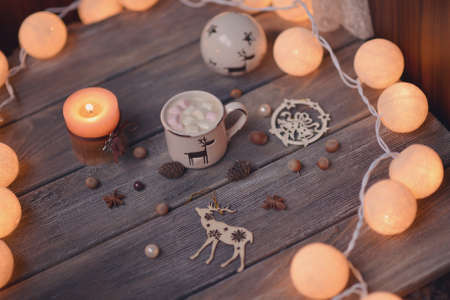 on wooden table lit garland and candle in a cup of coffee and nutsの写真素材