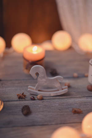 on wooden table lit candle and garland and wooden horsesの写真素材