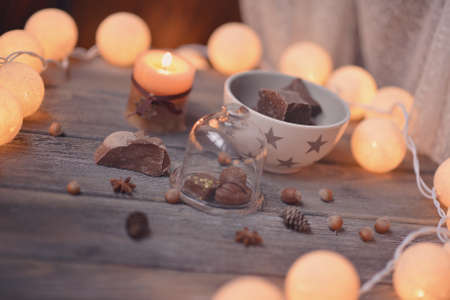 on wooden table lit garland and candle in a cup of coffee and chocolateの写真素材