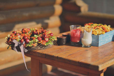 against the background of the house wooden table with a decorative basket with red applesの写真素材