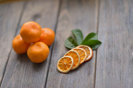 on wooden table is a slide and sliced tangerines with green leaves and nutsの写真素材