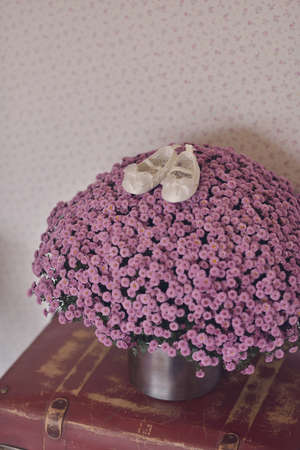 on the floor is a vase with a large bouquet of flowers and children\'s shoesの写真素材
