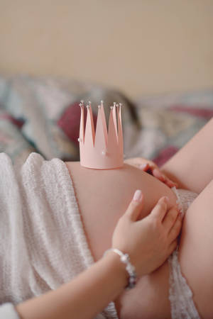 on the bed belly of a pregnant woman with a small crown