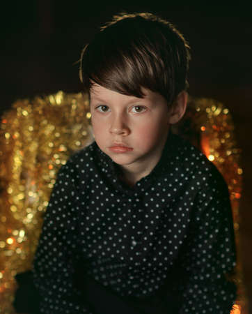 against the background of a burning garland Portrait of a boy in a black shirtの写真素材