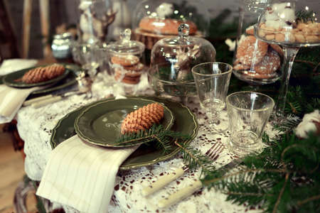 Christmas table setting in a rustic style with a green plate with cones and openwork napkinsの写真素材