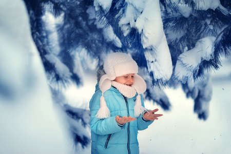happy boy in the winter forest among the snowy pines playing and smilingの写真素材