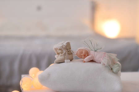 lit garland baby fur boots and sleeping doll on light backgroundの写真素材