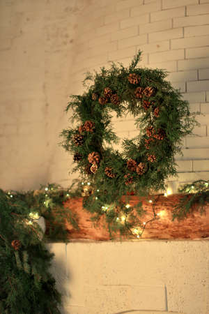in a room on the stone wall over the fireplace weighs Christmas wreath made of spruce and conesの写真素材