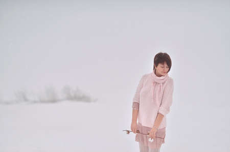 snow and fog beautiful woman in a sweater and with a branch in hand posingの写真素材