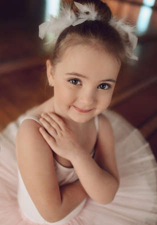 Portrait of a cute little ballerina in a white suit and with feathers in her hairの写真素材