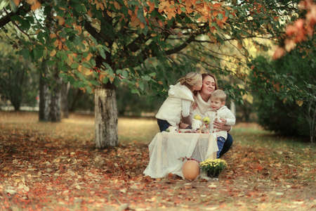 autumn warm day in the woods on a picnic table with fruit and utensils mother with her childrenの写真素材