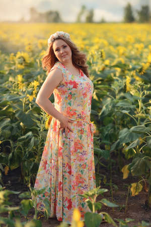beautiful woman with long hair and a wreath on his head on the field with sunflowersの写真素材