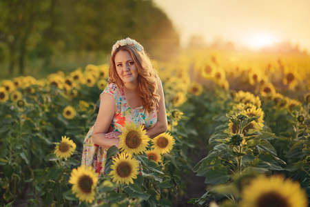 beautiful woman with long hair and a wreath on his head on the field with sunflowersの写真素材