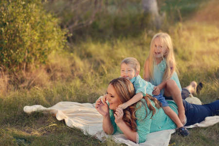 in the forest in a clearing in the sunlight plays a mother with childrenの写真素材