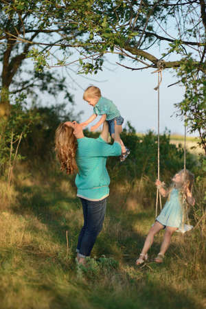 in the forest in a clearing in the sunlight plays a mother with childrenの写真素材