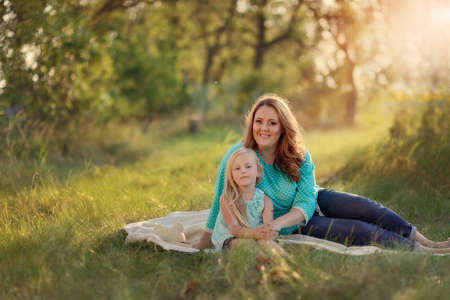 in the forest in a clearing in the sunlight plays a mother with childrenの写真素材