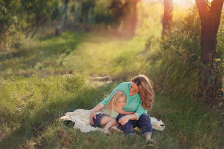 in the forest in a clearing in the sunlight plays a mother with childrenの写真素材