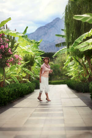 Alley in the park on a woman in a white skirt and pink blouse posingの写真素材