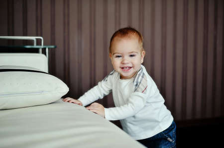 in a room near the white sofa is a small boy with red hair wearing a white shirtの写真素材