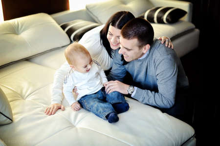 room on a white bed happy young family playing with his young sonの写真素材