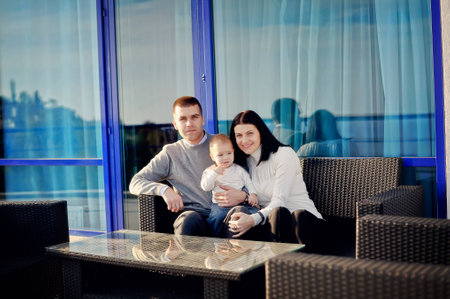 against the background of large blue boxes in wicker chairs sitting family with young sonの写真素材