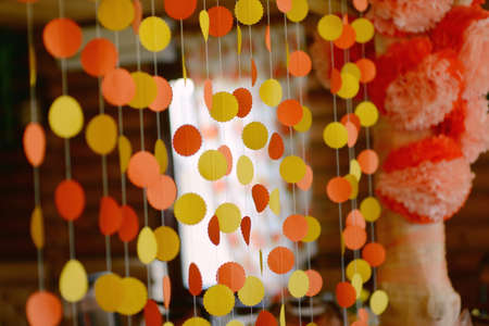 hut of wooden frame with festive decorations, paper garlands, flowers and balloons in orange and yellow flowersの写真素材