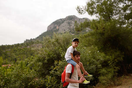 father with a backpack and a son on a walk in the mountainsの写真素材