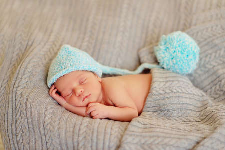 in bed sleeping baby in a blue cap with a large buboの写真素材